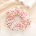 Close-up of floral print hair scrunchie with pink petals on soft chiffon fabric - Red