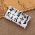 White claw clip with black ink calligraphy pattern on rustic brown linen background - White