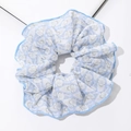 Detail eines hellblauen Scrunchie mit Blumenmuster, Stickerei und Wellensaum-Finish - Blau
