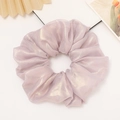 Detail of lavender scrunchie with metallic sheen and elegant pleats on white surface - Purple