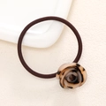 Detail view of tortoiseshell resin rose on a high-elasticity brown hair tie for women - Caramel color