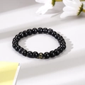 Detail of black obsidian beaded bracelet with gold Sanskrit engraving on minimalist background - Single Glossy Bead Symbol Style (4)