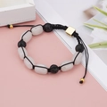 Detail of woven yoga bracelet with white crystal, black lava stones and gold metal clasp - Oval White Stone