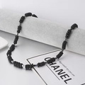 Bohemian kralenketting voor heren met natuursteen en zilveren klaverhanger op display - Zwarte Kokosnootschil & Hematiet Kruis