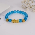 Detailansicht blauer Perlen mit goldenem Pixiu-Anhänger auf einem modischen Armband - Pixiu-Stil / Himmelblau