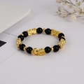 Nahaufnahme von Obsidian-Perlenarmband mit fünf goldenen Pixiu-Anhängern und Abstandshalter - Mehrfach PiXiu Stil / Schwarz