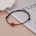 Verstelbare zwarte gevlochten armband met oranje basketbalkraal op beige ondergrond - Basketbalstijl
