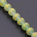 Macro detail of natural light green crystal beads with golden mantra engraving and smooth texture - Light Green
