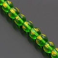 Macro shot of green translucent crystal beads with gold mantra carvings for jewelry DIY - Emerald Green