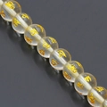 Macro view of transparent natural crystal beads with golden mantra engraving details - Clear