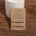 Close-up of handmade woven friendship bracelets with luminous blue heart beads on a kraft card - Luminous Dark Blue Heart