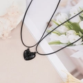 Detail of black heart magnetic couple necklaces with hand-carved promise pattern on a beige base - Classic Black
