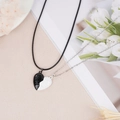 Close-up of magnetic heart necklaces with forever engraving and handshake pattern for couples - Black and White