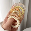 Close-up of assorted spiral hair coils featuring gold foil, floral patterns and solid cream - Yellow