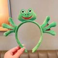 Detail view of plush green frog headband featuring embroidered eyes and cute webbed feet - Happy Frog Style