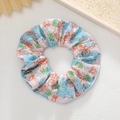 Détail d'un chouchou rose à fleurs avec motif dessin animé sur fond cuir blanc - Fleurs Bleu Orange Fond Rose Cartoon