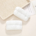 Close-up of soft white plush wristbands designed for face washing and water absorption - White