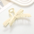 Matte cream bow-shaped hair claw clip on a stylish ceramic tray background - Off White