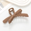 Matte brown bow-shaped hair claw clip with cross design on minimalist white background - Coffee