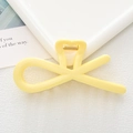 Close-up of a pale yellow hollow heart hair clip with a gold metal spring mechanism - Yellow