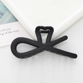 Detail of a matte black hair claw clip featuring an elegant heart and bow design - Black