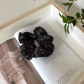 Dettaglio di un elastico in raso nero a pois su una rivista per acconciature moda - Nero