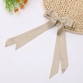 Detail showing elegant champagne satin bow hair clip with long ribbons on a straw hat - Khaki
