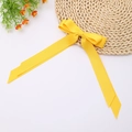 Close-up of bright yellow double-layered polyester bow hair clip with long ribbons - Gold