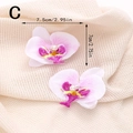 Vista dettagliata di fermagli per capelli con orchidee rosa e perle su tessuto beige - Stile C