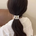 Close-up of a sleek silver ponytail cuff on a woman's low ponytail in a cozy indoor setting - Silver