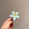 Close-up of light blue plumeria hair clip with yellow gradient center detail - Blue