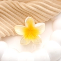 Macro detail van de acryl plumeria bloem haarklem met realistische hars textuur op stof - Bleekgele Frangipani