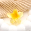 Haarklem met frangipani bloem van acryl in geel verloop op een beige gebreide stof - Geel