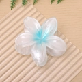 Detailansicht einer großen blau-weißen Plumeria-Haarklammer auf hellem Holztisch - Himmelblau