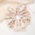 Detailopname van een grote bloemen scrunchie met roze roospatronen op crème chiffon stof - Roze Bloemen