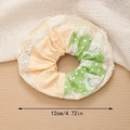 Detail van een 12 cm bloemen- en kant scrunchie met stippen op een houten ondergrond - Groen Patchwork Roos Scrunchie