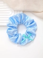 Detail eines hellblauen Satin-Haargummis mit hellgrüner Schleife auf einem Tablett - Blau