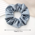 Detailweergave van een 13 cm grijsblauwe satijnen scrunchie met strass op witte decor - Premium Grijs