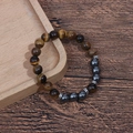 Detailed macro shot of 8mm tiger eye and hematite beads on a rustic wooden tray - Tiger Eye