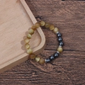 Detail of 8mm tiger eye beads and grey hematite stones on a wooden tray - Yellow Tiger Eye