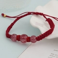 Detail eines roten handgewebten Armbands mit mattierten Perlen und Goldverschluss - Rote Schnur Erdbeerquarz Dreifachstein