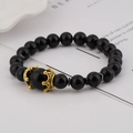 Detail of luxury men's bracelet with black beads and two golden crown alloy charms - Obsidian