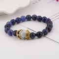 Detailed macro view of natural blue stone beads bracelet with a golden crown charm and white bead - Sodalite & White Turquoise