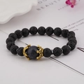 Close-up of black lava stone bracelet with blue lapis lazuli bead and golden crown charm - Lava Stone & Lapis Lazuli