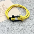 Détail d'un bracelet en corde de nylon tressé jaune avec manille en métal noir mat en forme de U - Jaune (Boucle en U en Alliage)