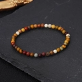 Handmade 4mm natural stone energy bead bracelet with multi-color beads on dark rock surface - Multicolor