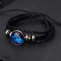 Détail du bracelet en cuir tressé avec breloque zodiaque lumineuse sur ardoise noire - Verseau