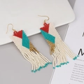 Detail showing handmade bohemian beaded tassel earrings with colorful geometric patterns - Cream Red Blue