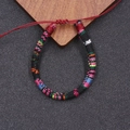 Detail eines handgefertigten Boho-Armbands mit rotem Schiebeknoten auf dunklem Grund - Schwarz/Bunt (9)