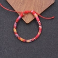 Nahaufnahme eines gewebten Boho-Freundschaftsarmbands mit verstellbarem Schiebeverschluss - Rot/Gelb Lila Rosa Blau (3)